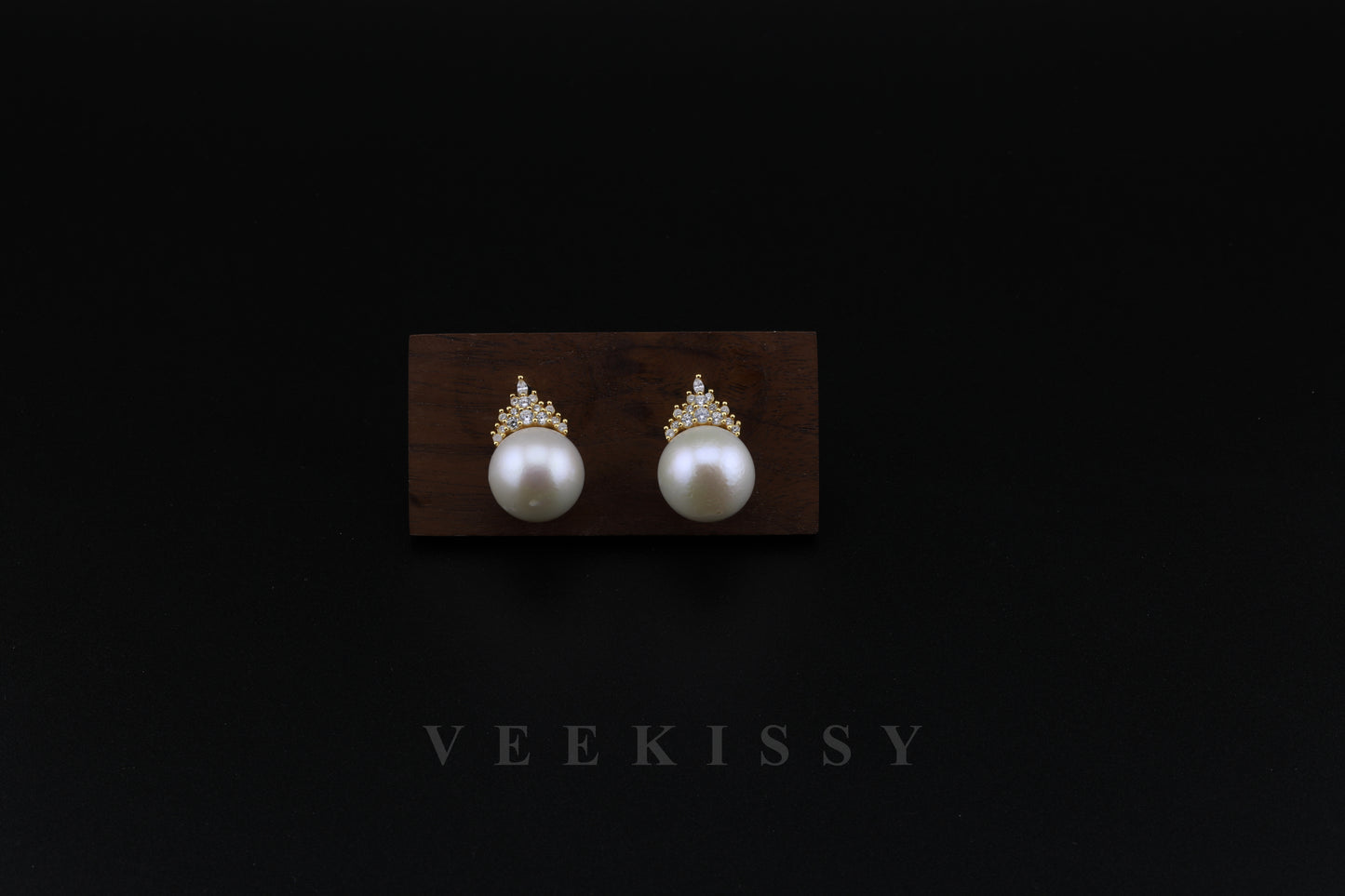 A pair of elegant freshwater pearl stud earrings with gold-plated sterling silver and delicate crystal accents, displayed on a wooden stand against a black background. Perfect for weddings, special occasions, and everyday luxury.