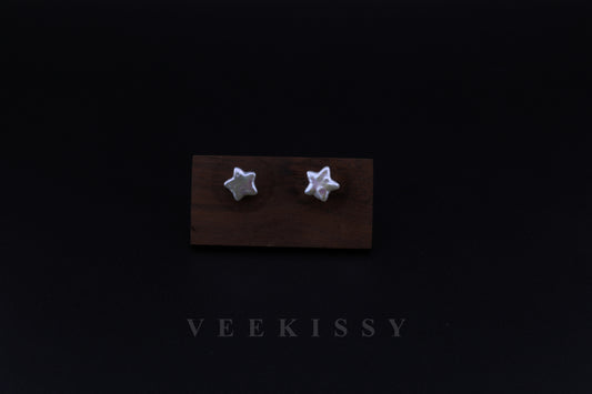 A pair of handcrafted star-shaped baroque pearl earrings displayed on a wooden stand against a black background, featuring natural freshwater pearls set on sterling silver studs.