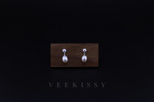 A pair of double freshwater pearl drop earrings, featuring a round stud pearl and an oval drop pearl, set on 925 sterling silver, displayed against a black background with a wooden stand.